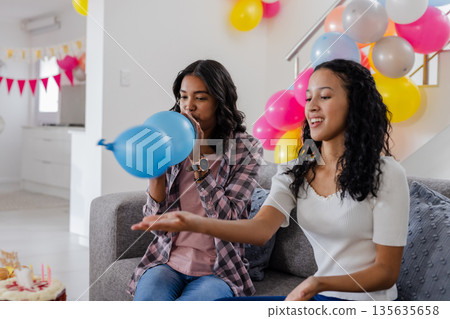 Two women decorating living room with colorful balloons for festive celebration Two women decorating living room with colorful balloons for festive celebration 135635658