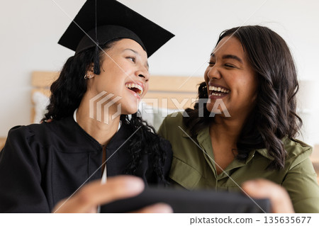 Graduation day, mother and daughter laughing and taking selfie at home Graduation day, mother and daughter laughing and taking selfie at home 135635677