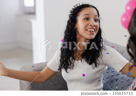 Smiling African American woman celebrating at home with confetti and balloons 135635713
