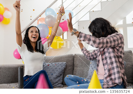 Celebrating at home, two women enjoying party with colorful balloons and confetti Celebrating at home, two women enjoying party with colorful balloons and confetti 135635724