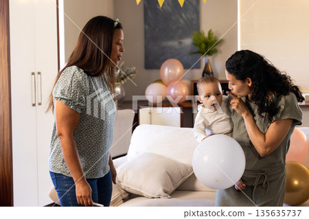 Celebrating at home, African American women with baby and balloons, family time Celebrating at home, African American women with baby and balloons, family time 135635737