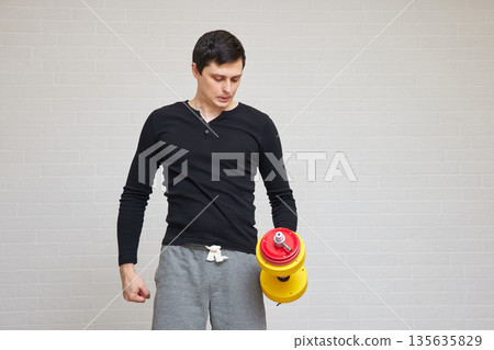Man holding dumbbell in hand, reflecting on home exercise Man holding dumbbell in hand, reflecting on home exercise 135635829