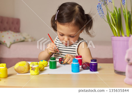 Little child girl paint Easter eggs at home. kid is preparing for Easter. Little child girl paint Easter eggs at home. kid is preparing for Easter. 135635844