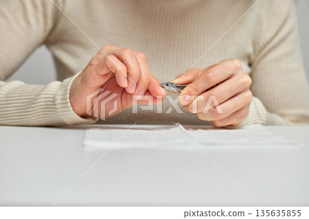 Woman using cuticle nippers to groom nails and fingers Woman using cuticle nippers to groom nails and fingers 135635855