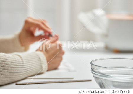 Woman hands caring for nails, performing self-care routine at home, focus on bowl, copy space Woman hands caring for nails, performing self-care routine at home, focus on bowl, copy space 135635856
