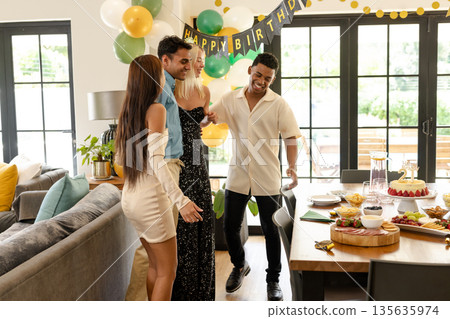 Celebrating birthday at home, friends smiling with festive decorations and food 135635974