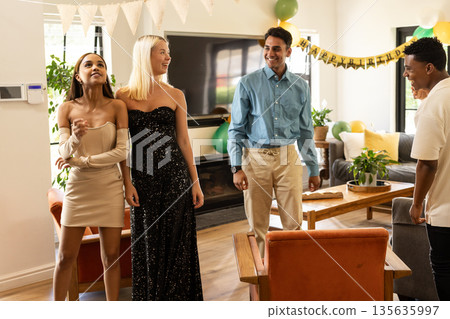Celebrating birthday at home, friends smiling with festive decorations around them Celebrating birthday at home, friends smiling with festive decorations around them 135635997