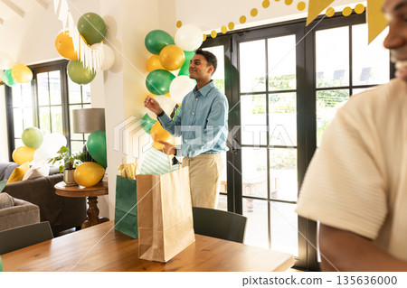 Man decorating living room with balloons and banners for festive celebration 135636000