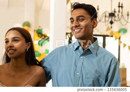 Smiling friends celebrating together at home with festive decorations in background 135636005