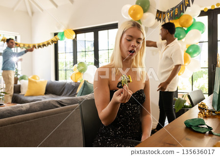 Holding party favor, woman in black dress with friends decorating for birthday party Holding party favor, woman in black dress with friends decorating for birthday party 135636017