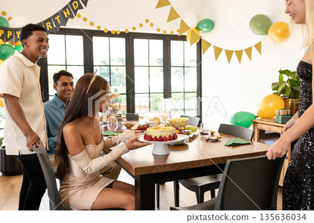 Friends gathering around birthday cake with decorations, celebrating and smiling happily 135636034