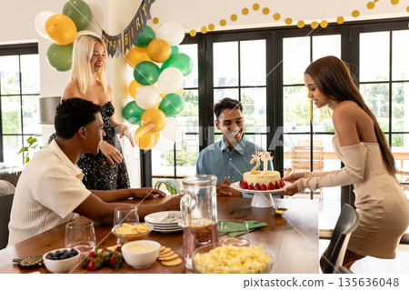 Friends celebrating birthday with cake and decorations, smiling and enjoying party Friends celebrating birthday with cake and decorations, smiling and enjoying party 135636048