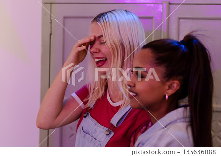 Two young women laughing and enjoying fun moment at party 135636088