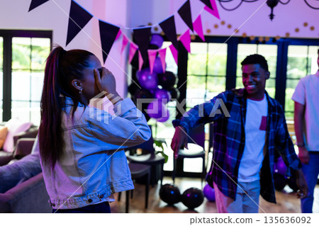 Friends celebrating at home, dancing and enjoying festive decorations and balloons 135636092