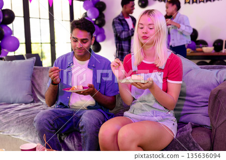 Friends enjoying cake at home party, surrounded by festive balloons and decorations Friends enjoying cake at home party, surrounded by festive balloons and decorations 135636094