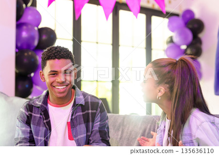 Teenagers celebrating at home, smiling and talking with colorful balloons around Teenagers celebrating at home, smiling and talking with colorful balloons around 135636110