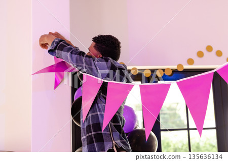 African American man decorating room with pink bunting for celebration event African American man decorating room with pink bunting for celebration event 135636134