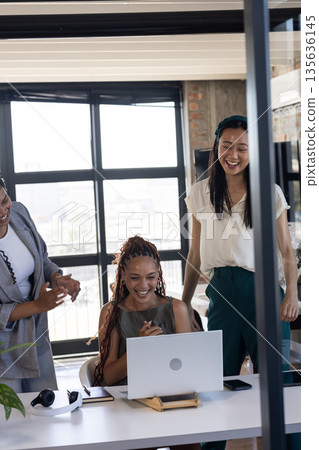 Celebrating success, diverse team applauding colleague at office desk with laptop 135636145