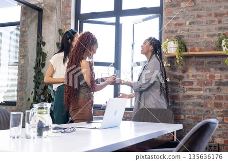 Colleagues celebrating success with handshake and smiles in modern office Colleagues celebrating success with handshake and smiles in modern office 135636176
