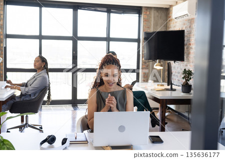 Celebrating success, businesswoman at office desk with laptop, feeling excited 135636177