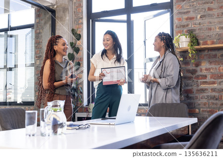 Sharing awards and smiles, diverse businesswomen celebrating success in modern office Sharing awards and smiles, diverse businesswomen celebrating success in modern office 135636211