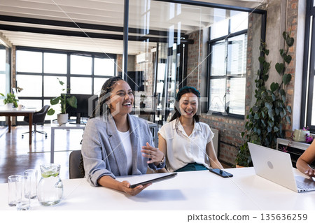 Colleagues in modern office celebrating success with laughter and teamwork 135636259