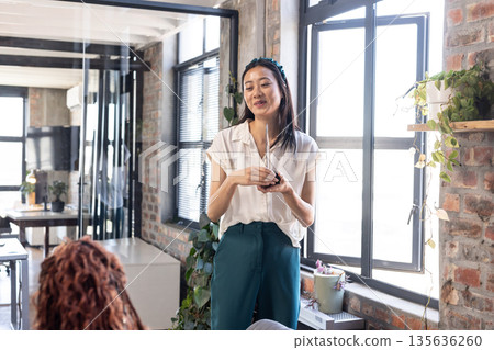 Businesswoman presenting ideas to colleagues in modern office, smiling confidently Businesswoman presenting ideas to colleagues in modern office, smiling confidently 135636260