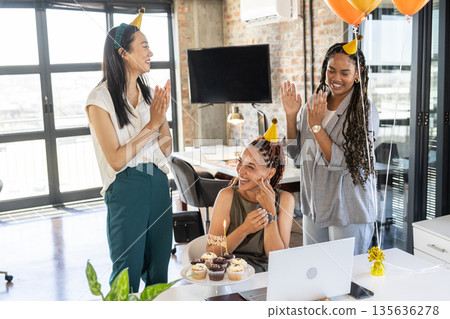 Celebrating birthday, colleagues in office clapping with cupcakes and party hats 135636278