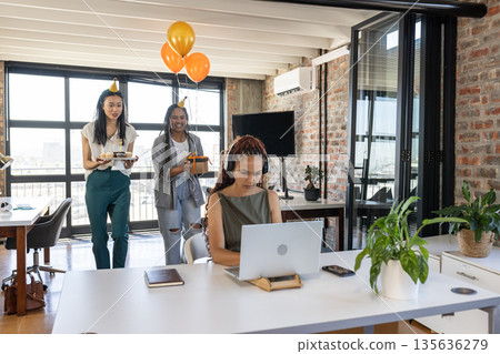 Colleagues surprising woman with cake and balloons in modern office celebration 135636279