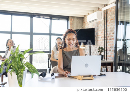 Smiling woman using laptop in modern office during business meeting Smiling woman using laptop in modern office during business meeting 135636300