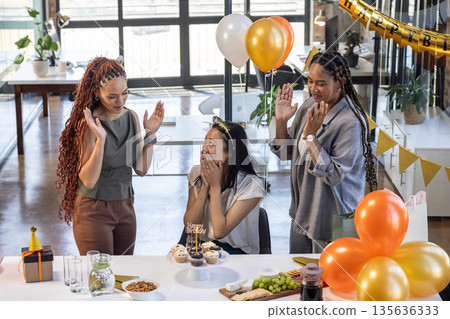 Surprising woman with birthday cupcakes and balloons, colleagues celebrating in office 135636333