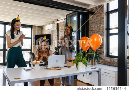 Colleagues celebrating birthday with cupcakes and balloons in modern office 135636344