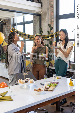 Colleagues enjoying birthday celebration with cake and decorations in modern office 135636360