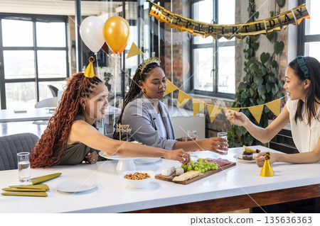 Colleagues celebrating birthday at office with snacks and festive decorations 135636363