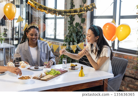 Colleagues enjoying birthday celebration with snacks and drinks at office party 135636365