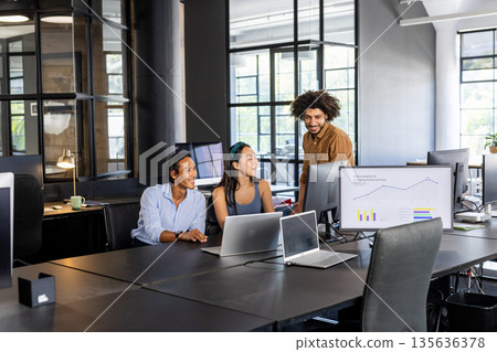 Collaborating in modern office, diverse team analyzing data on computer screens Collaborating in modern office, diverse team analyzing data on computer screens 135636378