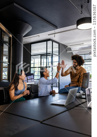 In modern office, diverse colleagues celebrating success with high five and smiles 135636387