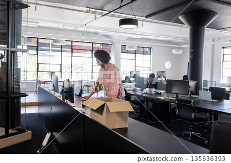 Man packing belongings into box in modern office, preparing for move 135636393