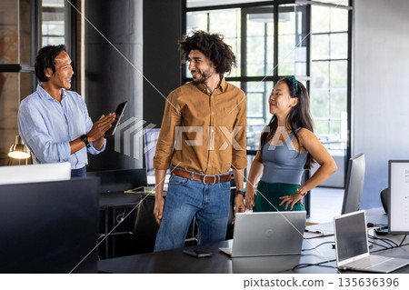 Business team collaborating in modern office, discussing project with enthusiasm 135636396