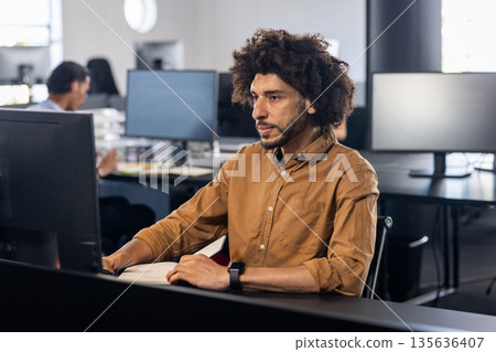 Focused African American man working on computer in modern office environment 135636407
