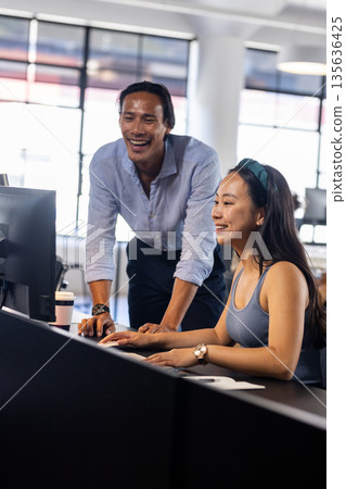 Colleagues collaborating on computer in modern office, sharing ideas and solutions 135636425