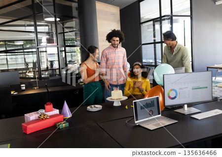 Colleagues celebrating birthday in modern office with cake and gifts on table Colleagues celebrating birthday in modern office with cake and gifts on table 135636466