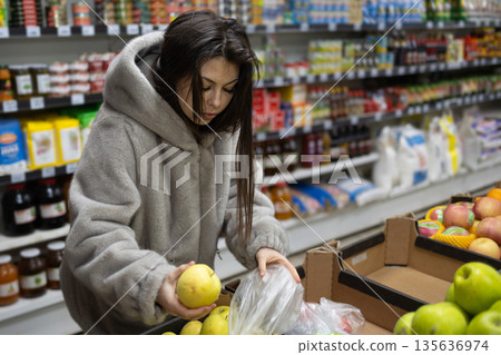 Woman Shopping for Apples in a Grocery Store During the Day 135636974