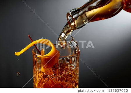 Whiskey or bourbon pouring into a crystal glass. Whiskey or bourbon pouring into a crystal glass. 135637050