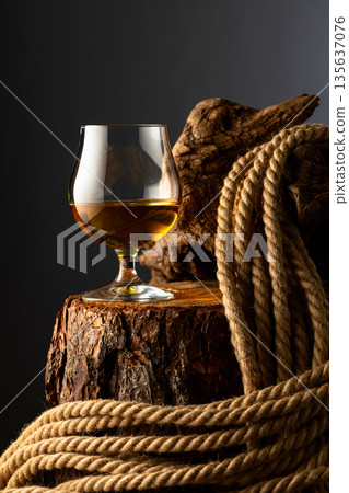 Brandy snifter and rope on a old stumb. 135637076