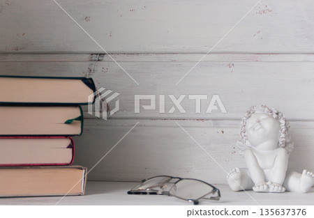 Elegant still life with pile of books, eyeglasses and angel statue. Cozy interior with books on shelf. Education concept. Aesthetic lifestyle. Minimalism in home design. Classic glasses and books Elegant still life with pile of books, eyeglasses and angel statue. Cozy interior with books on shelf. Education concept. Aesthetic lifestyle. Minimalism in home design. Classic glasses and books 135637376