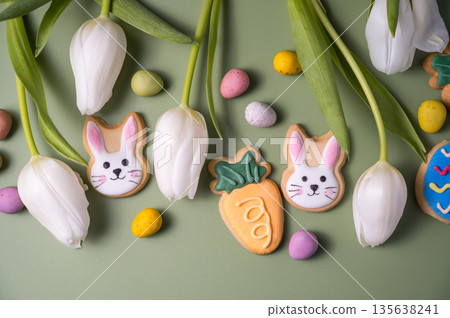 Easter spring holiday background with easter cookies: buny, carrot and egg with white tulip flowers, flat lay 135638241