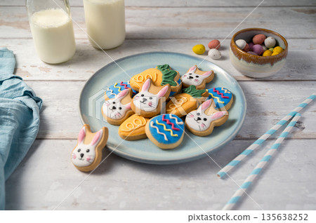 Easter cookies with bottles of milk on white wooden background and mini chocolate easter candy eggs. Spring holidays background Easter cookies with bottles of milk on white wooden background and mini chocolate easter candy eggs. Spring holidays background 135638252