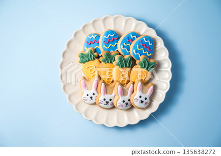 Easter spring holiday background with easter cookies in a plate: bunny, carrot and eggs Easter spring holiday background with easter cookies in a plate: bunny, carrot and eggs 135638272