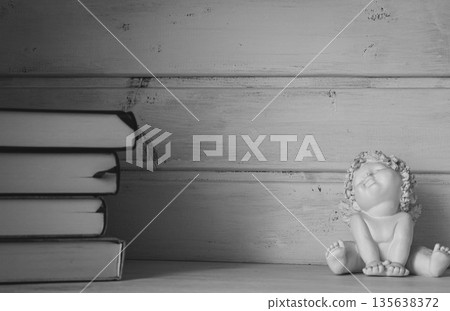 Elegant still life with pile of books and angel statue, monochrome. Cozy interior with books on shelf, black and white. Education concept. Aesthetic lifestyle. Minimalism in home design. Elegant still life with pile of books and angel statue, monochrome. Cozy interior with books on shelf, black and white. Education concept. Aesthetic lifestyle. Minimalism in home design. 135638372